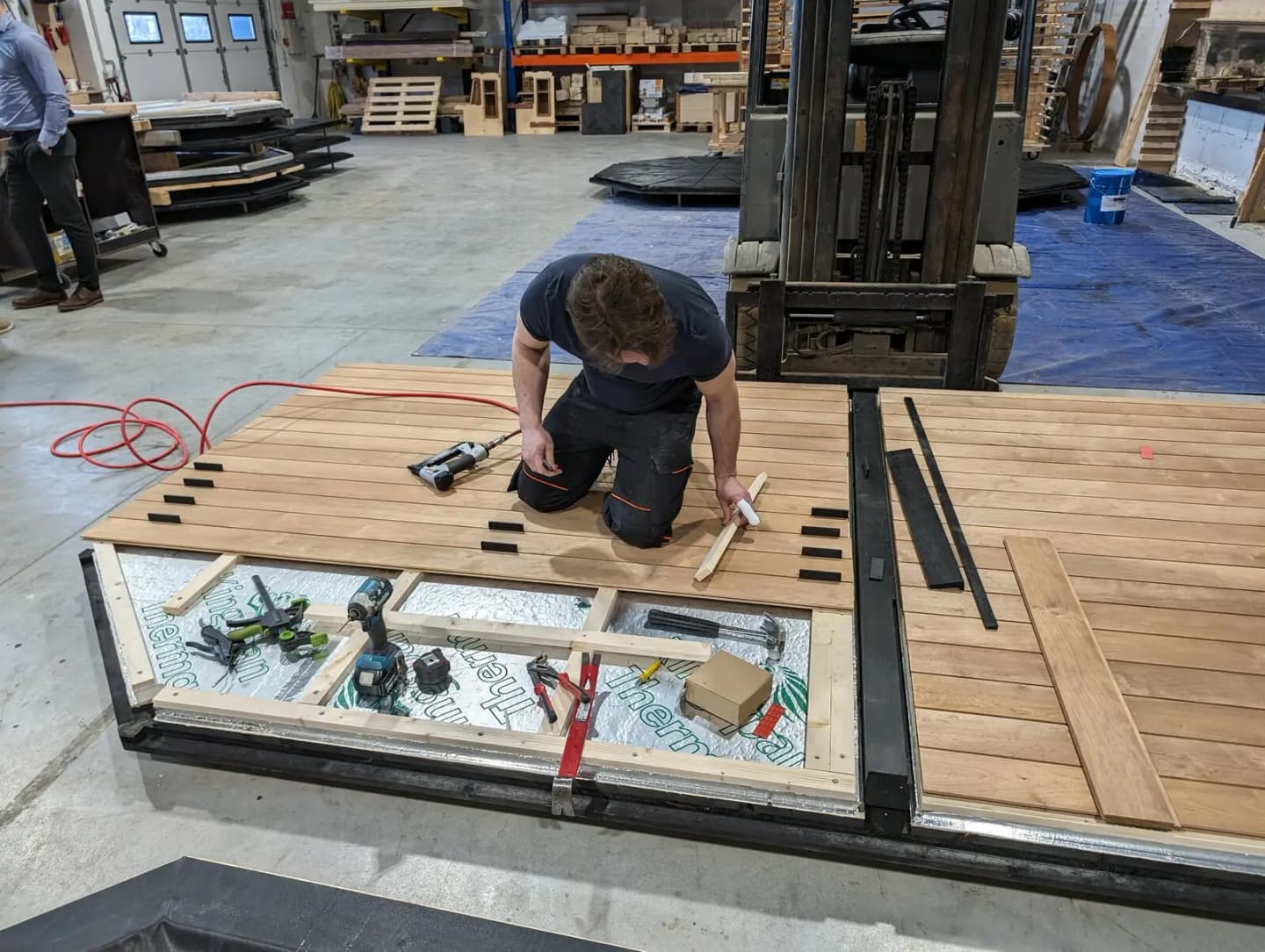 A craftsperson building the floor frame of a sauna in a workshop